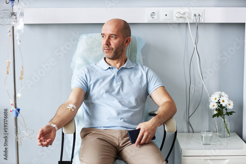Obraz na płótnie Portrait of adult man sitting in comfortable chair with IV drip during treatment