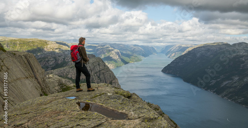 Caucasian hiker posing on ridge of a mountain overlooking the Lysefjord  Norway.