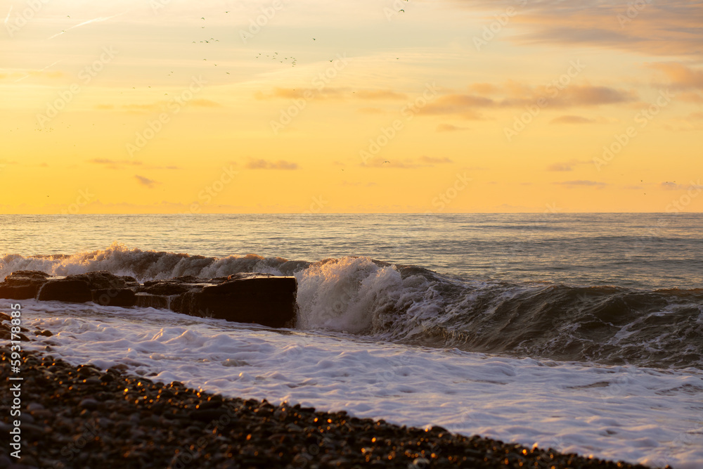 Big waves with foam on the pebbly beach On the Sunset