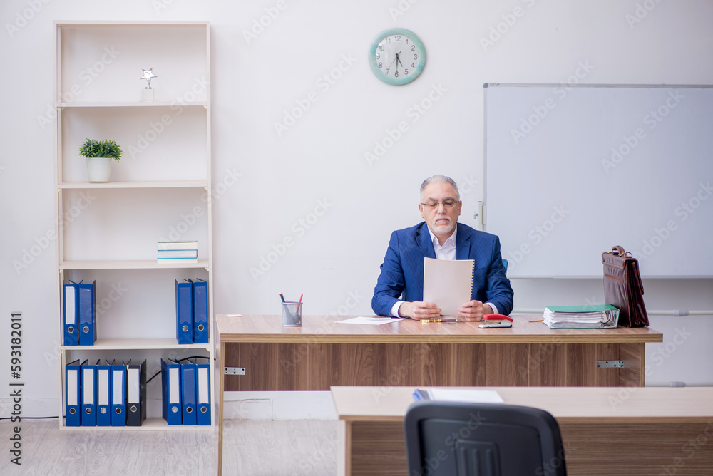 Old male teacher in the classroom Old male teacher in the classroom