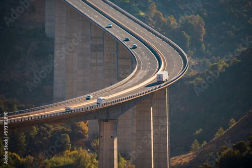 Картината върху платно Huge viaduct crossing a ravine with a truck with a refrigerated semi-trailer and several other vehicles circulating on the road, elevated view