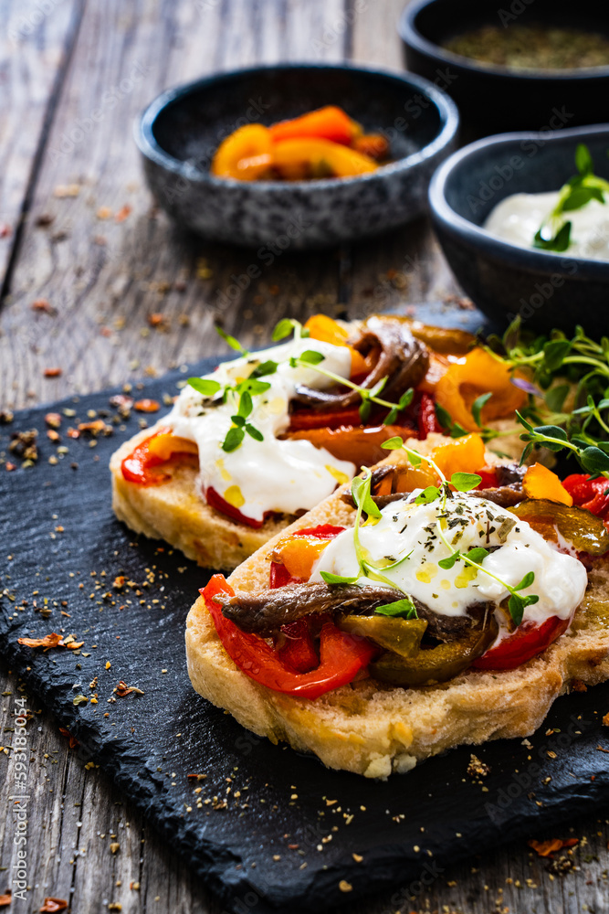 Tasty sandwiches - toasted bread with burrata cheese, anchovies, bell pepper, olives, tomatoes and thyme on wooden table
Tasty sandwiches - toasted bread with burrata cheese, anchovies, bell pepper, olives, tomatoes and thyme on wooden table