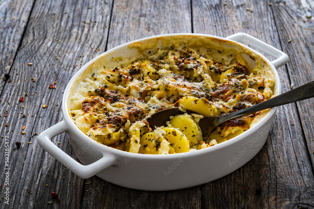 Potato casserole with mozzarella cheese and bechamel sauce on wooden table Potato casserole with mozzarella cheese and bechamel sauce on wooden table