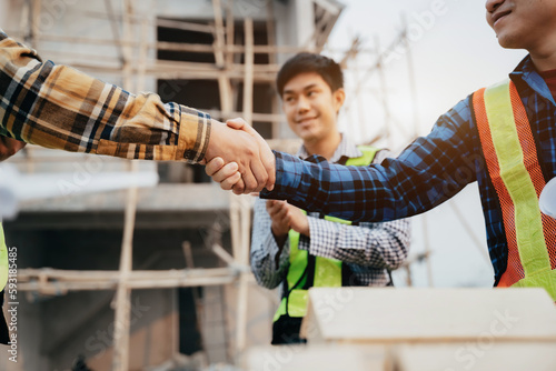 Construction workers, architects and engineers shake hands while working for teamwork and cooperation after completing an agreement in an office facility, successful cooperation concept.
