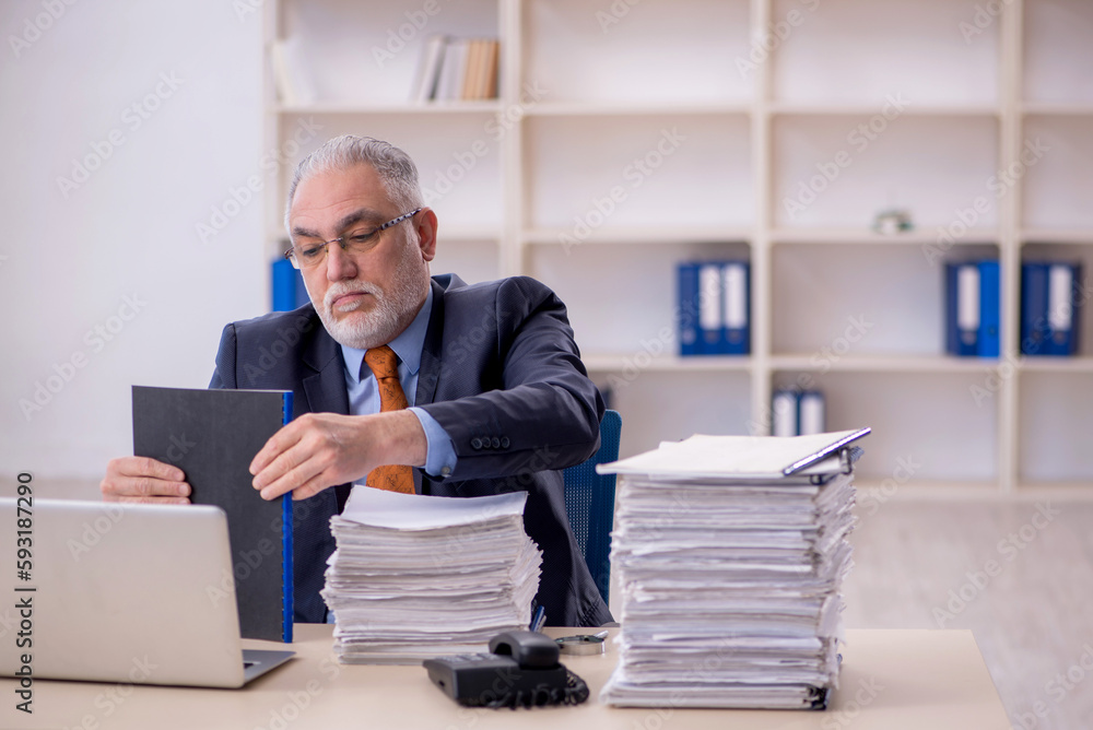 Old male employee unhappy with excessive work in the office Old male employee unhappy with excessive work in the office