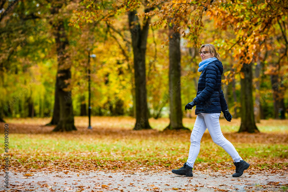 Fototapeta premium Beautiful woman walking in city park 