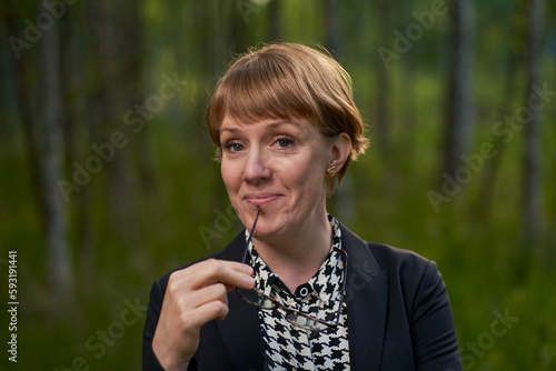 portrait of a female buissness woman holding her glasses to her mouth and smiling