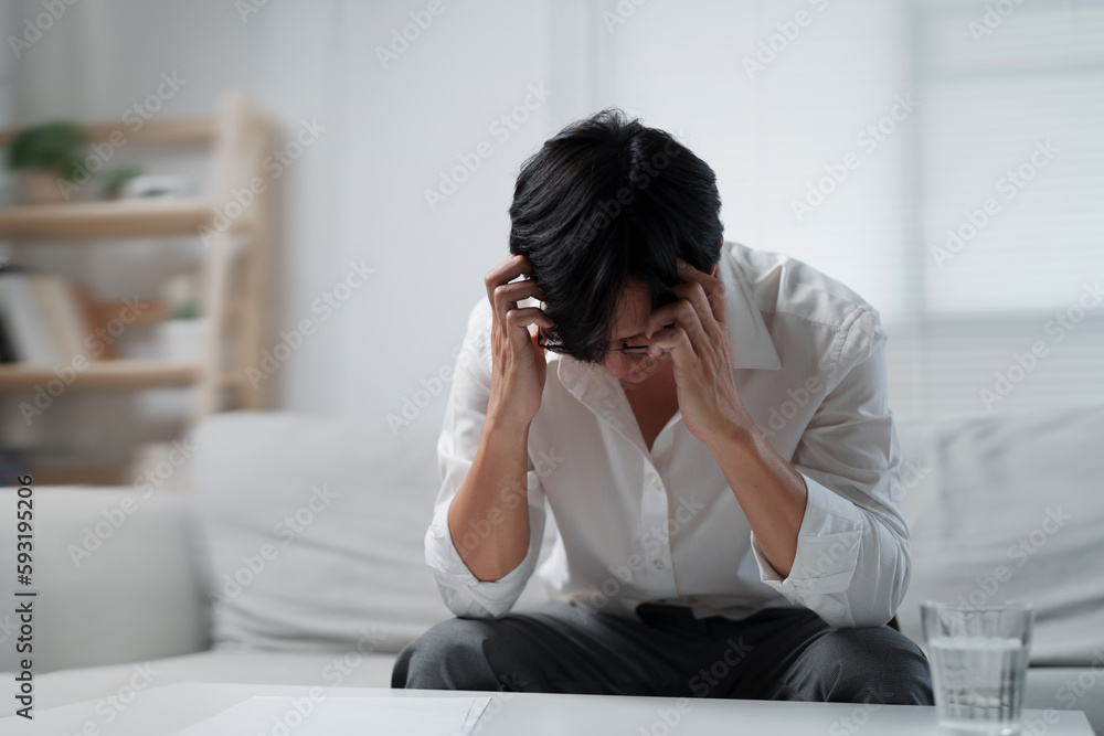 Young man sitting on sofa suffering from migraine after work.. Young man sitting on sofa suffering from migraine after work..