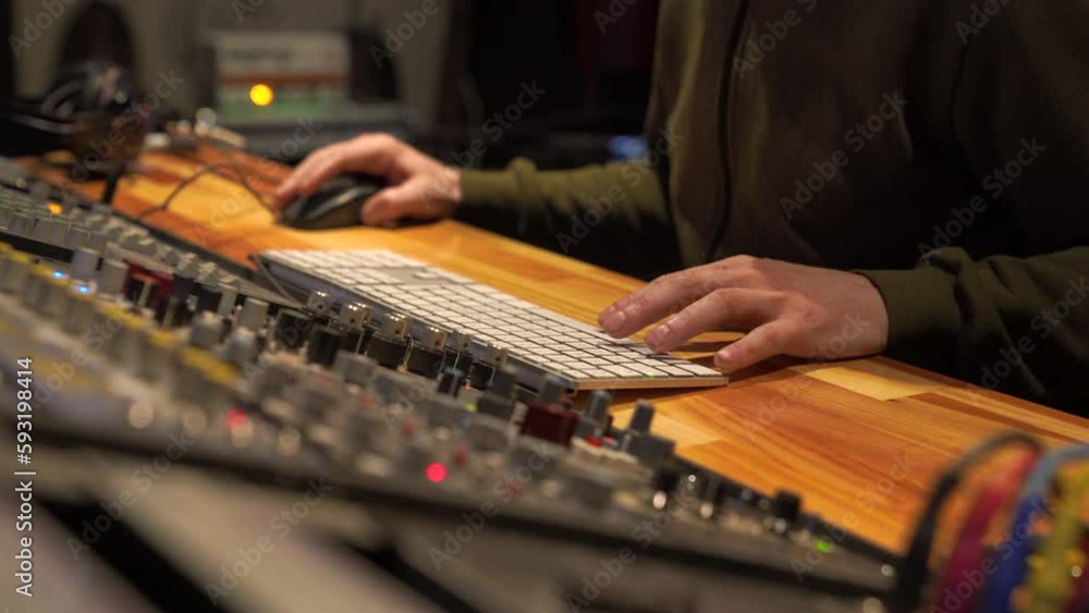 Man working on mixing sound recording in recording studio with hands next to mixing table changing settings Man working on mixing sound recording in recording studio with hands next to mixing table changing settings