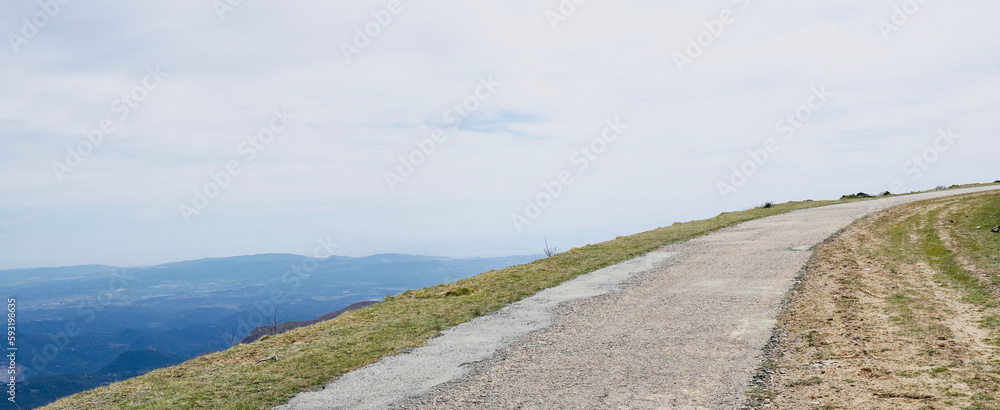 Fototapeta premium Sphalted road up the mountain with views of part of the Maresme, Barcelona. Hiking route in Montseny, Catalonia, Spain. Space for text.