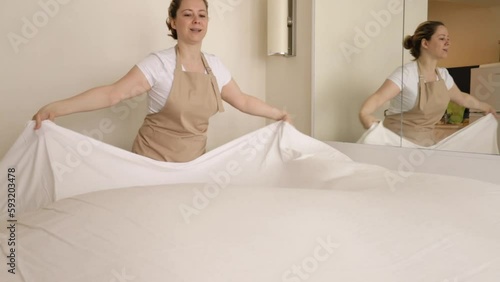 maid hands making bed, cleaning service, chambermaid in bedroom straightens bed linen