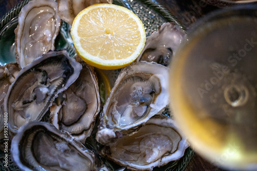 Open oysters on a plate with lemon and glass of champagne top view