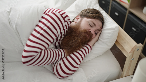Young redhead man lying on bed sleeping at bedroom