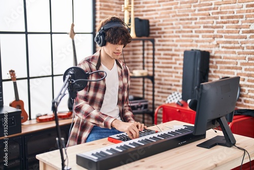 Photography Young hispanic man musician composing song at music studio