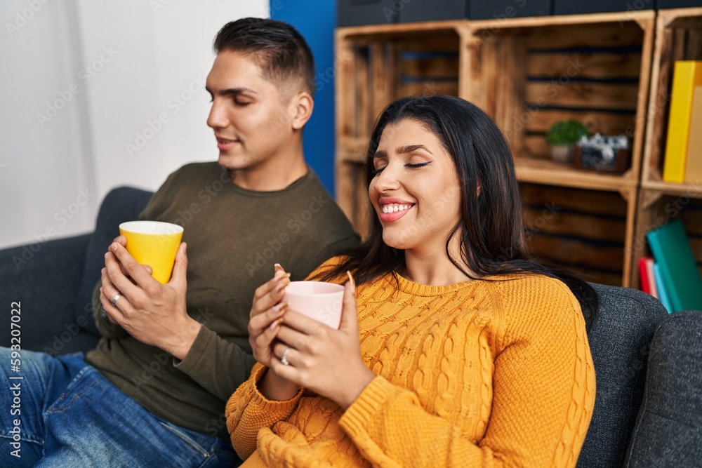 Man and woman couple drinking coffee sitting on sofa at home Man and woman couple drinking coffee sitting on sofa at home