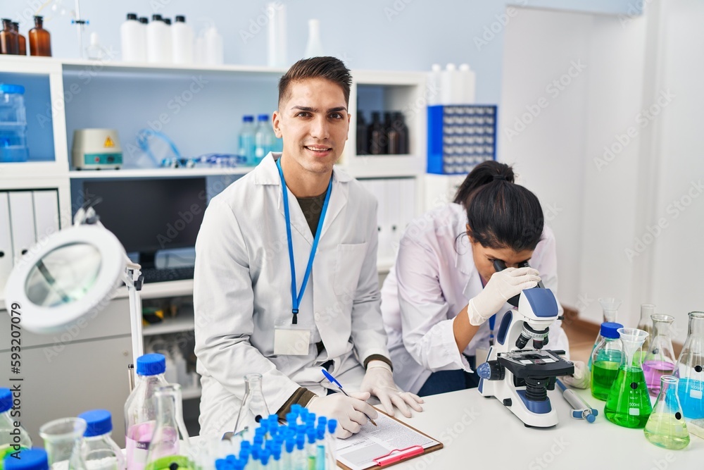 Man and woman scientists partners using microscope working at laboratory Man and woman scientists partners using microscope working at laboratory
