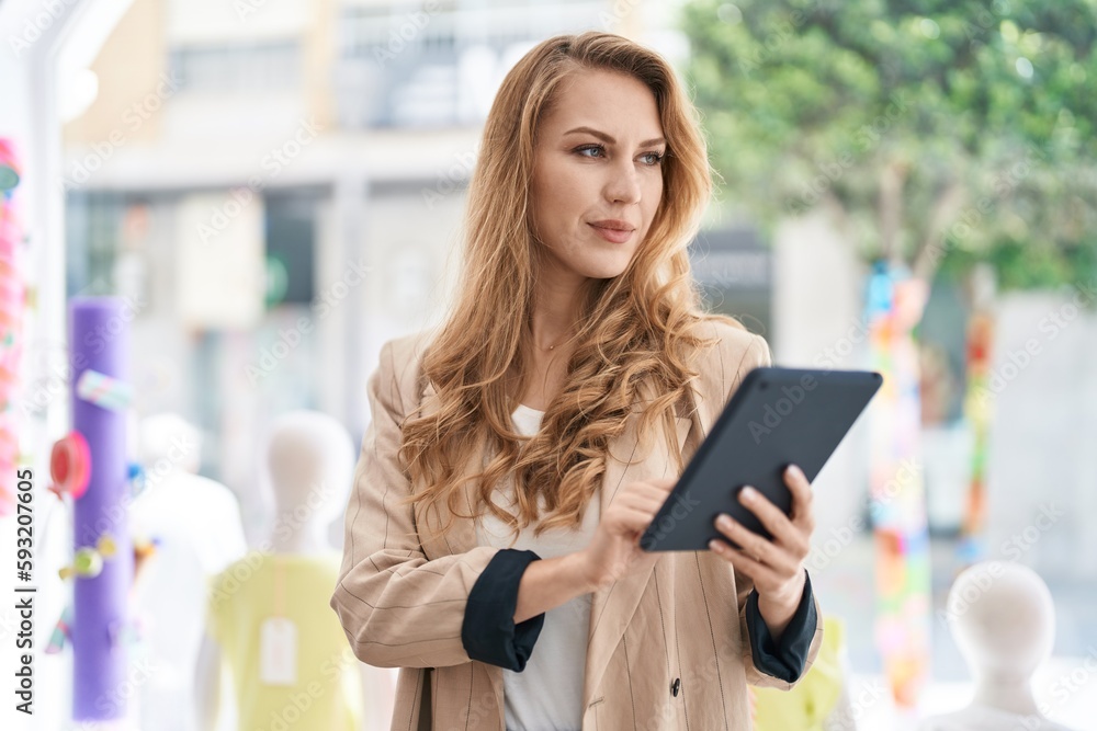 Young blonde woman shop assistant using touchpad working at clothing store Young blonde woman shop assistant using touchpad working at clothing store