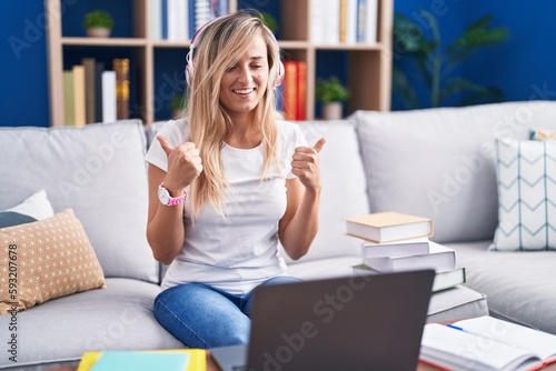 Young blonde woman studying using computer laptop at home success sign doing positive gesture with hand, thumbs up smiling and happy. cheerful expression and winner gesture.