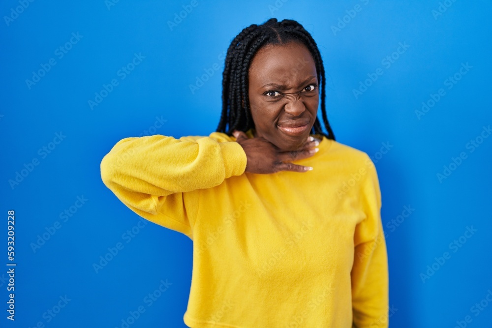 Obraz premium Beautiful black woman standing over blue background cutting throat with hand as knife, threaten aggression with furious violence