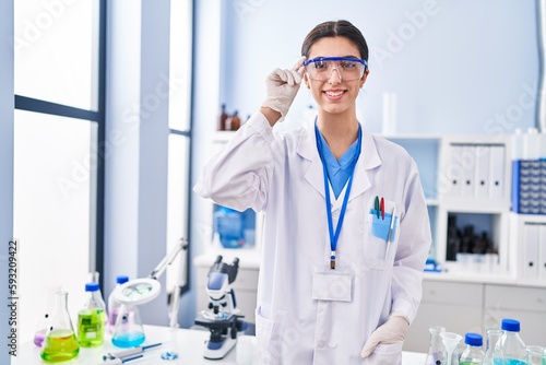 Young beautiful hispanic woman scientist smiling confident standing at laboratory