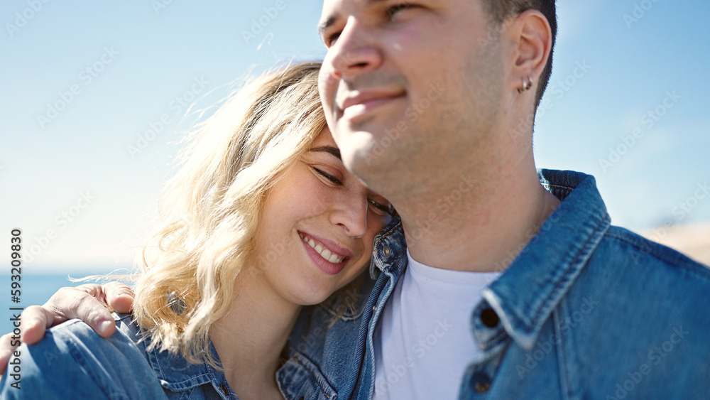 Man and woman couple smiling confident hugging each other at seaside