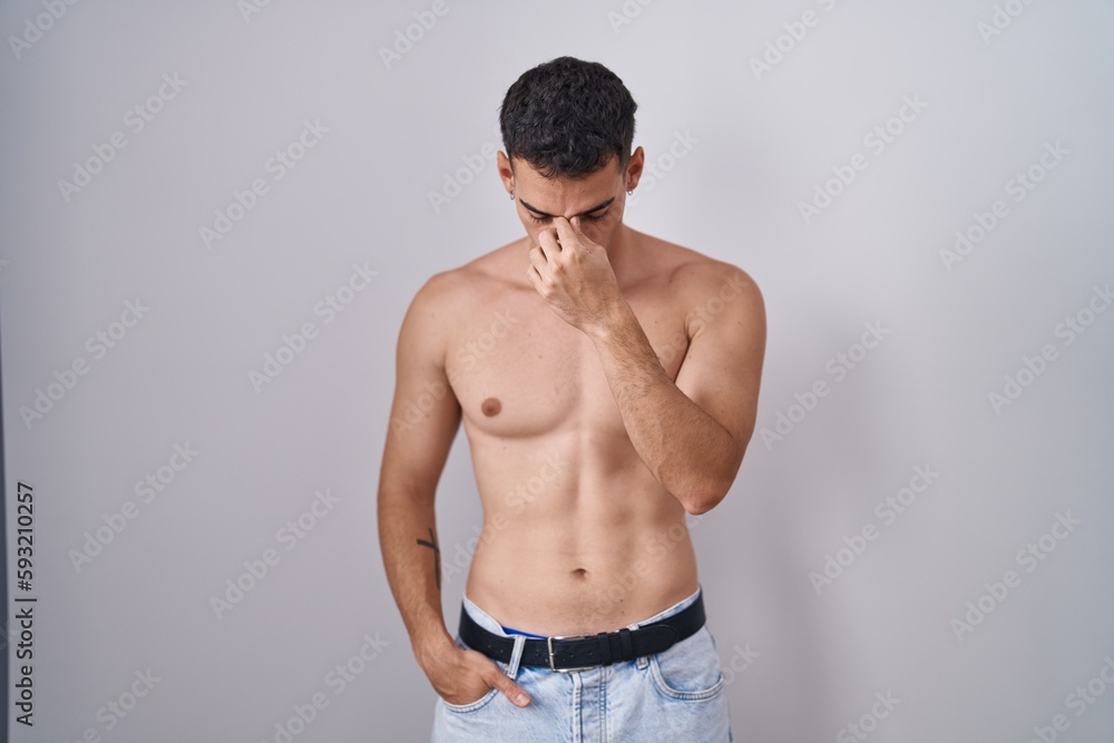 Fototapeta premium Handsome hispanic man standing shirtless tired rubbing nose and eyes feeling fatigue and headache. stress and frustration concept.
