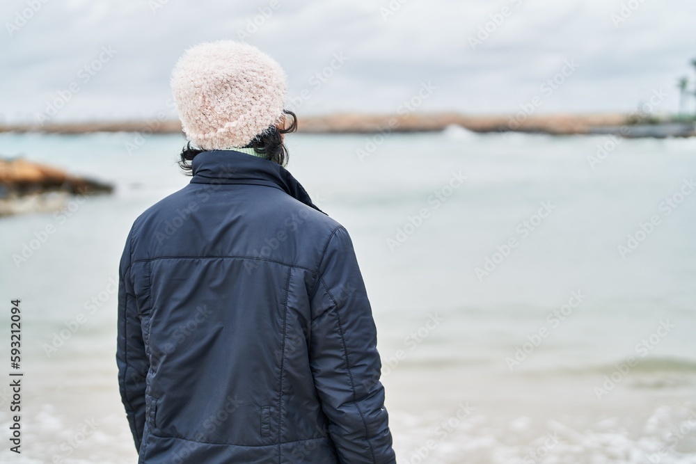 Young beautiful hispanic woman standing on back view at seaside Young beautiful hispanic woman standing on back view at seaside