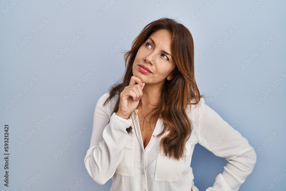 Hispanic woman standing over isolated background with hand on chin thinking about question, pensive expression. smiling with thoughtful face. doubt concept. Hispanic woman standing over isolated background with hand on chin thinking about question, pensive expression. smiling with thoughtful face. doubt concept.