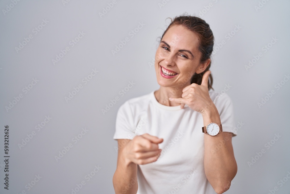 Beautiful brunette woman standing over isolated background smiling doing talking on the telephone gesture and pointing to you. call me. Beautiful brunette woman standing over isolated background smiling doing talking on the telephone gesture and pointing to you. call me.