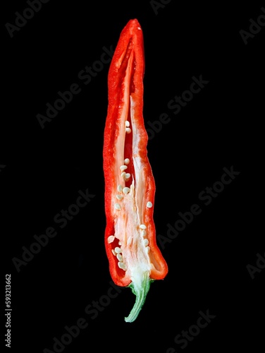 Closeup of a hot red pepper covered in water droplets, isolated on a black background