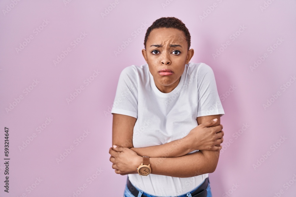Beautiful african american woman standing over pink background shaking and freezing for winter cold with sad and shock expression on face Beautiful african american woman standing over pink background shaking and freezing for winter cold with sad and shock expression on face