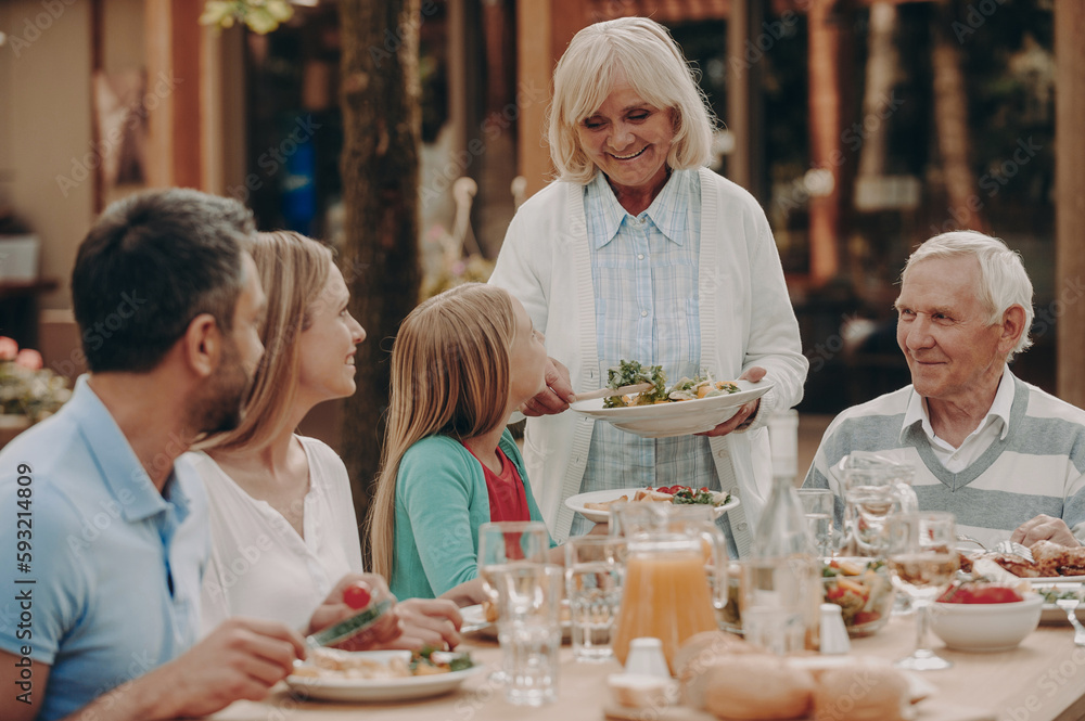 Happy multi-generation family enjoying meal while having dinner outdoors together
