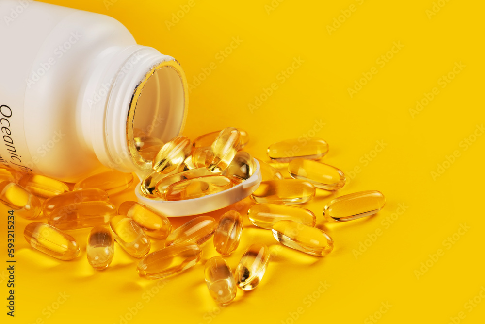 Fish oil capsules with omega 3 and vitamin D on yellow background Fish oil capsules with omega 3 and vitamin D on yellow background