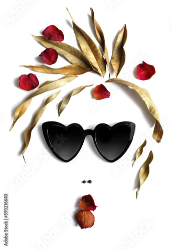 A woman's face made of different objects: black sunglasses in the shape of hearts, dry leaves, rose petals, black pepper.