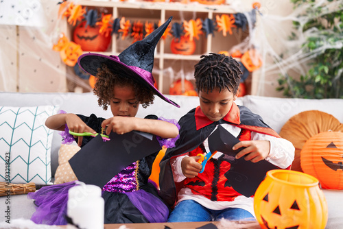 Adorable african american boy and girl having halloween party cutting paper at home