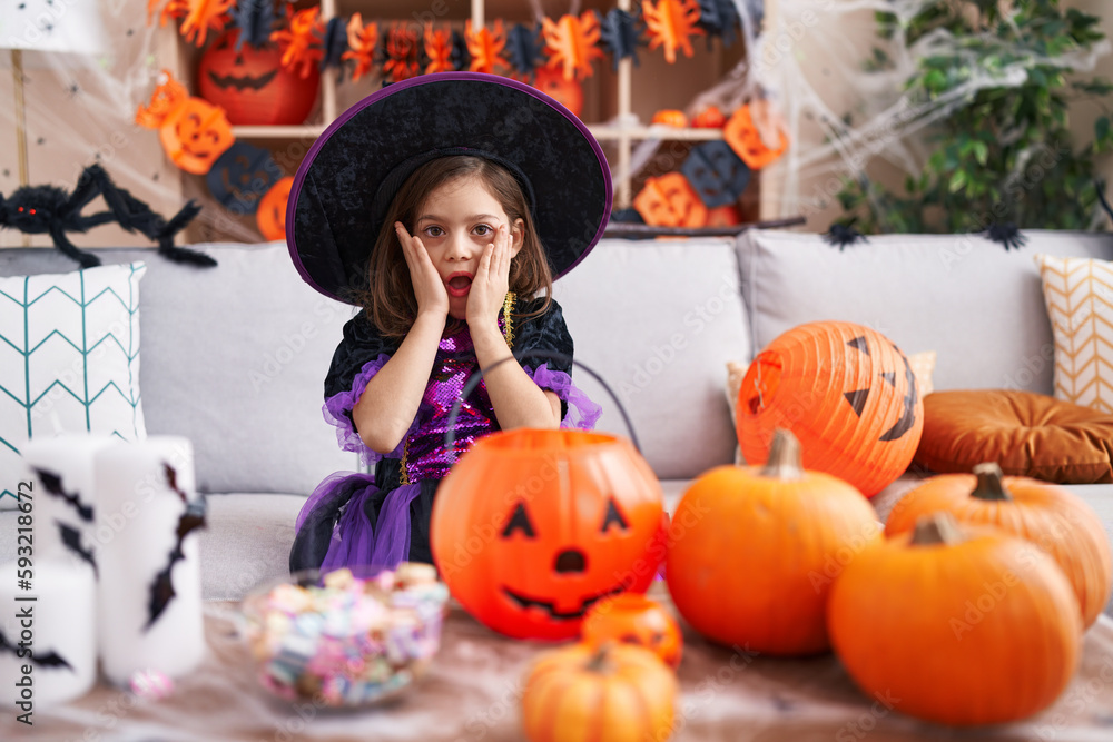 Adorable hispanic girl having halloween party with surprise expression at home