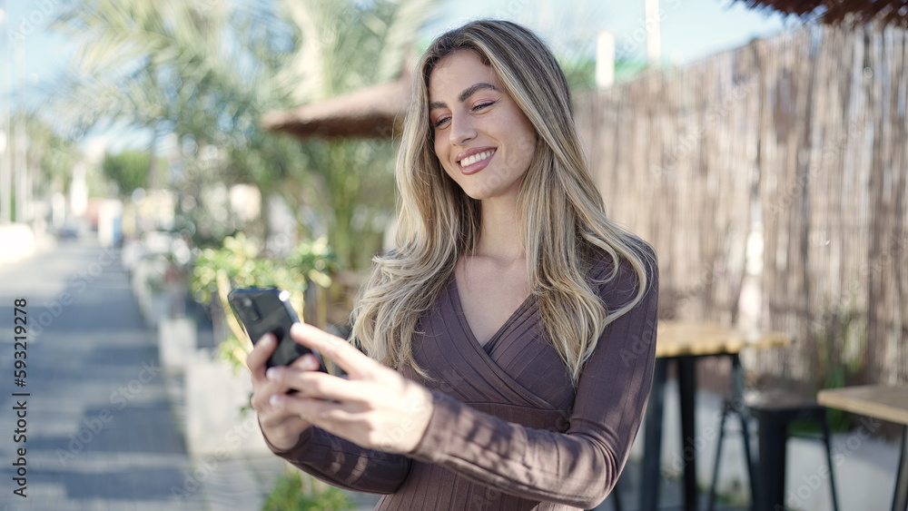 Fototapeta premium Young blonde woman smiling confident using smartphone at coffee shop terrace
