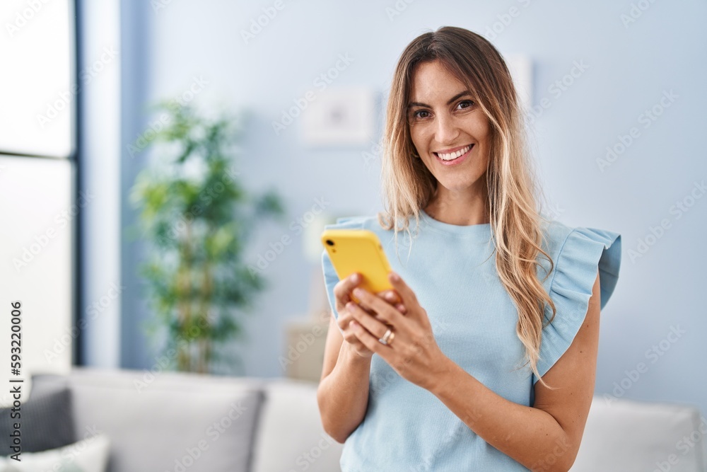 Young woman using smartphone standing at home Young woman using smartphone standing at home
