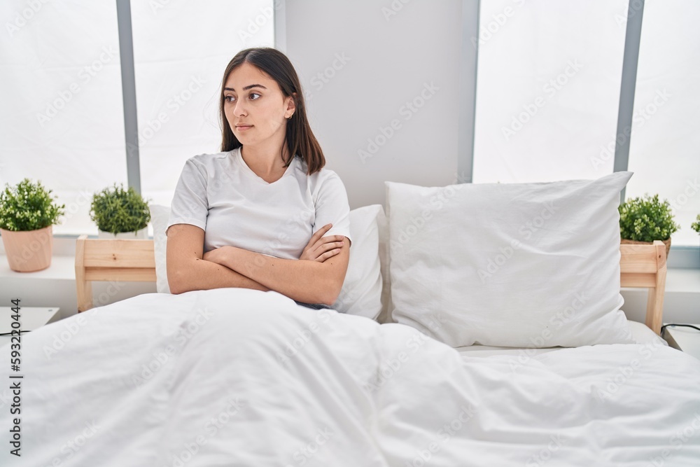 Young hispanic woman sitting on bed stressed with arms crossed gesture at bedroom Young hispanic woman sitting on bed stressed with arms crossed gesture at bedroom