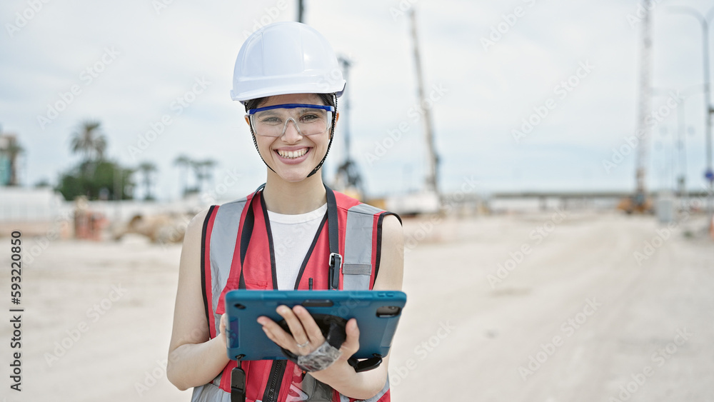 Young beautiful hispanic woman builder smiling confident using touchpad at street Young beautiful hispanic woman builder smiling confident using touchpad at street