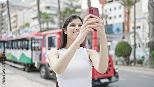 Young beautiful hispanic woman smiling confident recording video by smartphone at street