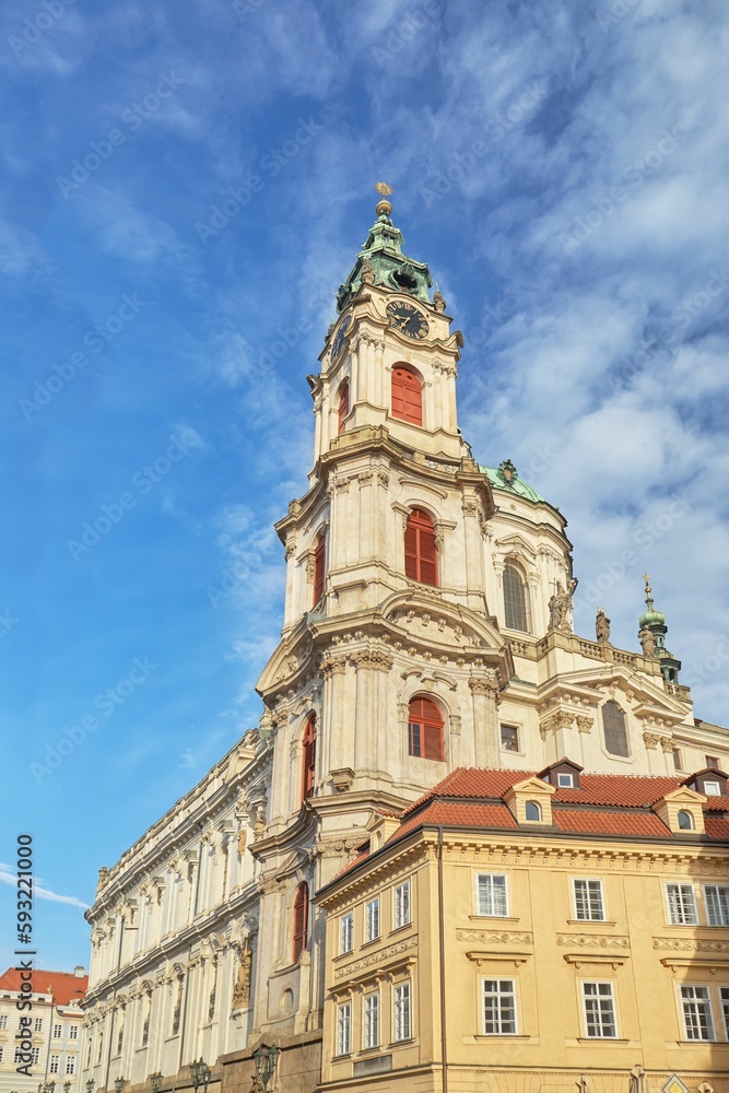 Vertical low angle shot of the historic St. Nicholas Church against a bright blue sky in Prague