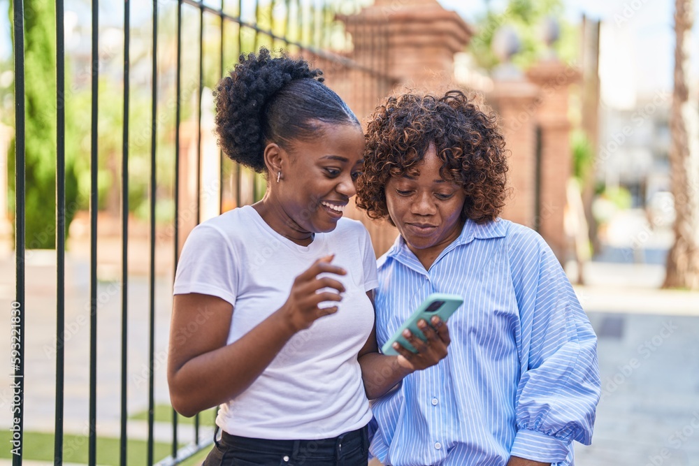 African american women mother and daughter using smartphone at street African american women mother and daughter using smartphone at street
