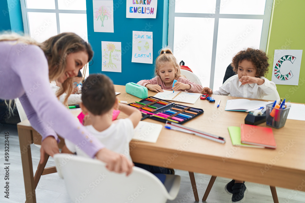 Fototapeta premium Woman and group of kids having lesson sitting on table at classroom
