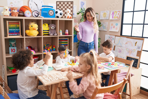 Woman and group of kids having vocabulary lesson at kindergarten