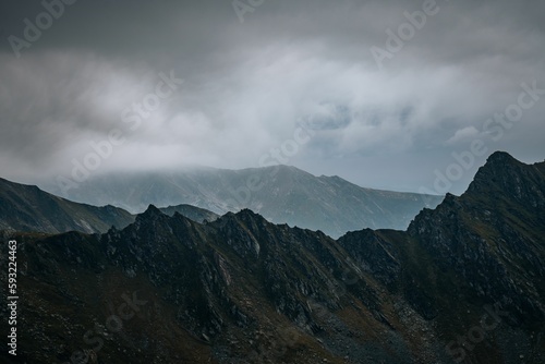Scenic view of a mountain range covered with clouds on a foggy day