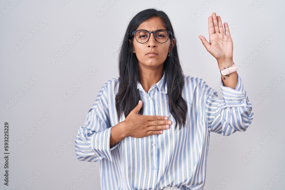 Young hispanic woman wearing glasses swearing with hand on chest and open palm, making a loyalty promise oath Young hispanic woman wearing glasses swearing with hand on chest and open palm, making a loyalty promise oath