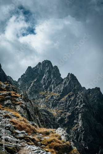 Vertical shot of big mountains with rocky peaks under the cloudy sky during the daytime