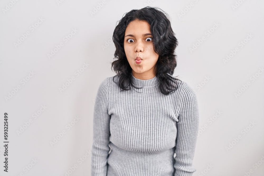 Hispanic woman with dark hair standing over isolated background making fish face with lips, crazy and comical gesture. funny expression. Hispanic woman with dark hair standing over isolated background making fish face with lips, crazy and comical gesture. funny expression.