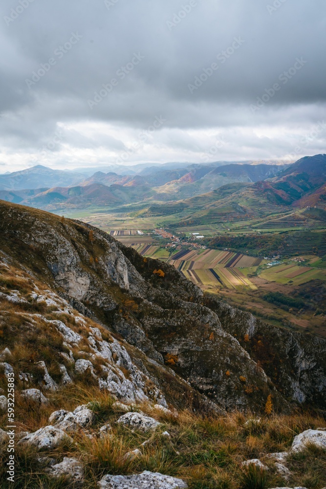 Vertical of a small village surrounded by the big mountains under the gloomy cloudy sky